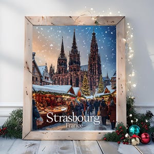 May include: A framed print of Strasbourg, France, during a winter market. The image features the Strasbourg Cathedral, market stalls, and people. The print is in a light-colored wooden frame, with Christmas decorations and lights.