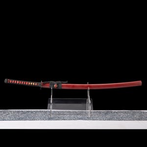 Peut inclure: Un katana japonais avec un fourreau et un manche laqu&eacute;s rouges. Le manche est envelopp&eacute; d'un cordon noir avec des accents rouges en forme de losange. L'&eacute;p&eacute;e est expos&eacute;e sur un pr&eacute;sentoir en acrylique transparent sur fond noir.
