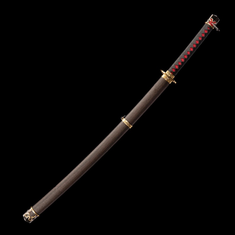 May include: A Japanese katana sword with a dark brown wooden handle and scabbard. The handle is wrapped in black fabric with red diamond accents. Gold-colored metal accents adorn the hilt and scabbard tip. The sword is set against a black background.