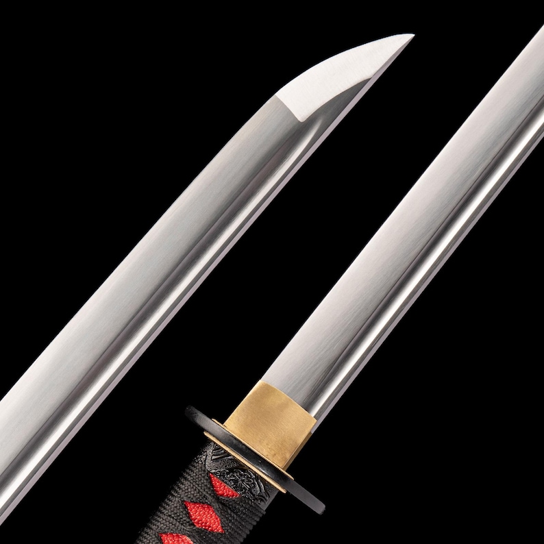 Peut inclure: Gros plan sur un katana, une &eacute;p&eacute;e japonaise. La lame argent&eacute;e est polie, le manche noir est orn&eacute; de d&eacute;tails rouges. La garde est dor&eacute;e et la pointe est ac&eacute;r&eacute;e. Fond noir uni.