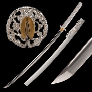 Könnte beinhalten: Ein weißes Katana mit einem silbernen und goldenen Tsuba, oder Schwerthüter, mit einem floralen Design. Das Katana wird mit seiner Scheide und einem weißen Griff gezeigt.