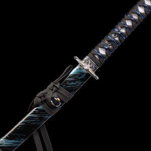 以下が含まれることがあります： 黒と青の柄と刃を持つ日本刀のクローズアップ。柄は青いアクセントが付いた黒いコードで包まれています。刃は青と黒の大理石模様です。刀には銀色の鍔が付いています。