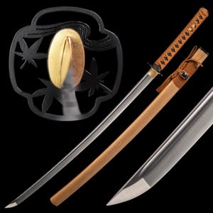 May include: A Japanese katana sword with a polished steel blade and a wooden scabbard. The handle is wrapped in brown fabric. A black metal tsuba with a gold accent and maple leaf design is visible.