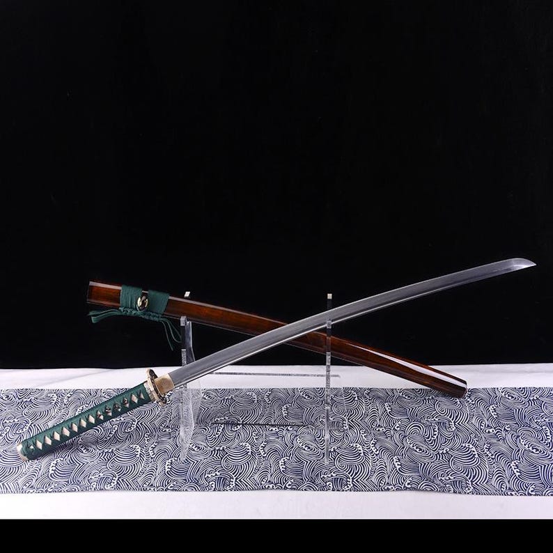 May include: A traditional Japanese katana sword with a brown wooden scabbard and a green wrapped handle. The sword is displayed on a stand with a wave pattern background.