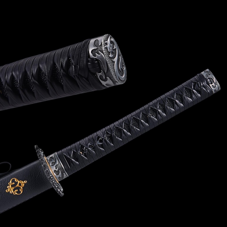 May include: A black katana sword with intricate silver and gold detailing. The handle is wrapped in black leather, and the blade is partially visible. The sword has a decorative silver end cap and a gold emblem near the hilt.