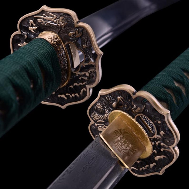 May include: Close-up of a katana sword with a green and gold handle. The handle is decorated with a dragon and wave design. The sword is sharp and has a black blade.
