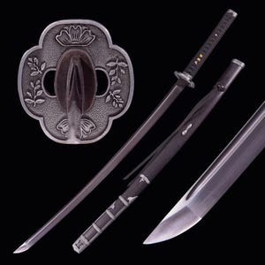 以下が含まれることがあります： 黒い柄と鞘が付いた日本の刀、刀。 刃は銀色で、ガードは花と葉のデザインが施された装飾的な銀色の金属です。 刀は黒い背景に表示されています。