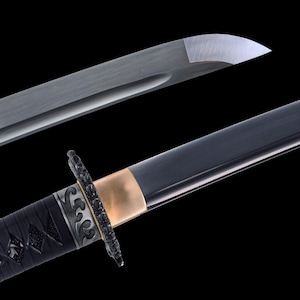 May include: Close-up of a Japanese katana sword. The blade is silver and the handle is black with intricate detailing. A gold-colored band separates the handle from the blade. The sword is set against a black background.