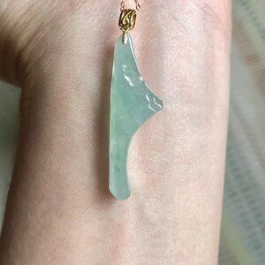 Peut inclure: Collier avec pendentif en jade vert clair et cha&icirc;ne dor&eacute;e. Le pendentif en jade est de forme irr&eacute;guli&egrave;re avec une surface lisse et polie. La cha&icirc;ne dor&eacute;e est d&eacute;licate et mesure environ 45 cm de long.