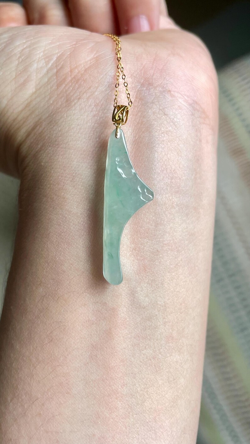 Peut inclure: Collier avec pendentif en jade vert clair et cha&icirc;ne dor&eacute;e. Le pendentif en jade est de forme irr&eacute;guli&egrave;re avec une surface lisse et polie. La cha&icirc;ne dor&eacute;e est d&eacute;licate et mesure environ 45 cm de long.