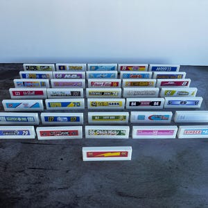 Peut inclure: Une collection de tuiles rectangulaires blanches avec divers motifs et textes colorés. Les tuiles présentent une variété de marques et de slogans, notamment "Filter Fun", "Gasprin", "Chick Hicks" et "Dinco King".