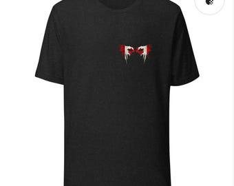 Peut inclure: T-shirt gris foncé avec un petit motif abstrait sur la poitrine. Le motif présente des éléments rouges et blancs, représentant peut-être un drapeau ou un emblème. Le t-shirt a des manches courtes et un col rond.