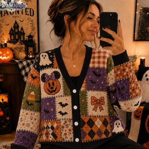 May include: A long-sleeve button-down cardigan featuring a patchwork design with Halloween-themed patterns including pumpkins, ghosts, bats, bows, and argyle prints in orange, purple, green, and black colors with a black V-neck trim.