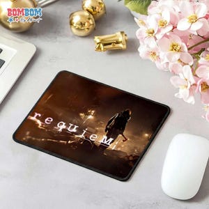 May include: A rectangular mousepad featuring a dark, cinematic image with the word "requiem" in white. A figure with an axe is visible. The mousepad is next to a white computer mouse.