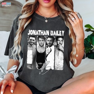 May include: Dark gray t-shirt featuring a black and white image of Jonathan Bailey. The image is divided into four vertical panels. The name "JONATHAN BAILEY" is printed above the image in white block letters, with a signature below.