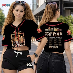 May include: Black baseball-style crop top with red trim, featuring the text "Descendants Zombies + Camp Rock Worlds Collide Concert Tour 2026." The top has a button-up front and a graphic of characters. Black shorts with the number "66" are also visible.