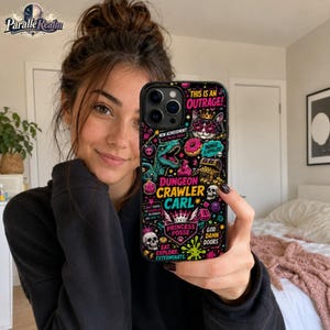 May include: A black smartphone case featuring a vibrant, multi-colored graphic print with the text "THIS IS AN OUTRAGE!", "DUNGEON CRAWLER CARL", "PRINCESS POSSE", "GOD DAMN DOORS", "EAT, EXPLORE, EXTERMINATE", and various illustrations including a cat, dinosaur, and skulls.