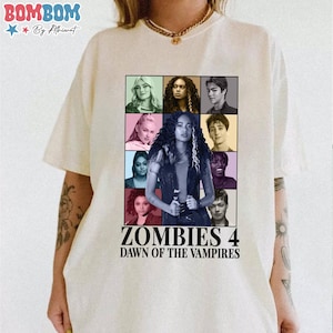 May include: Cream-colored t-shirt featuring a colorful graphic from the movie "Zombies 4: Dawn of the Vampires." The graphic includes a grid of character portraits and the movie title in bold, black font. The shirt has short sleeves and a crew neck.
