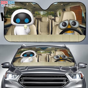 May include: Car sunshade featuring cartoon characters Eve and Wall-E inside a car. Eve is holding a lightbulb, and Wall-E is at the steering wheel. The sunshade is beige and black, designed to fit a car's windshield.