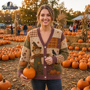 May include: A beige V-neck cardigan featuring a patchwork design with a scarecrow, sunflowers, a black bird, and plaid patterns. The knit sweater has a button-down front and is worn in a pumpkin patch filled with orange pumpkins and corn stalks.