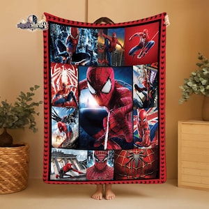 Puede incluir: Una manta roja y negra con tem&aacute;tica de Spider-Man. La manta presenta m&uacute;ltiples im&aacute;genes de Spider-Man en varias poses de acci&oacute;n. El borde es rojo con iconos de ara&ntilde;as negras. La manta est&aacute; sujeta por una persona.