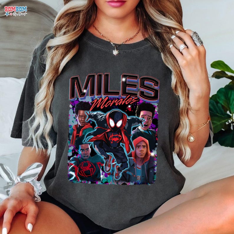 A person wearing a black t-shirt with a graphic design featuring characters from the Spider-Man movie franchise.