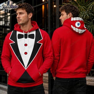 Pode incluir: Uma camisola com capuz vermelha com uma impressão gráfica de uma frente de smoking com laço preto, painel de camisa branca e dois botões vermelhos. O capuz exibe um gráfico grande de um olho azul rodeado por dentes brancos num fundo vermelho.