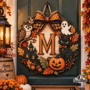 May include: A circular Halloween door wreath featuring a large orange letter M in the center, an owl, a ghost, a black cat, a jack-o'-lantern, a haunted house, and autumn leaves, all topped with a large orange and black polka dot bow.