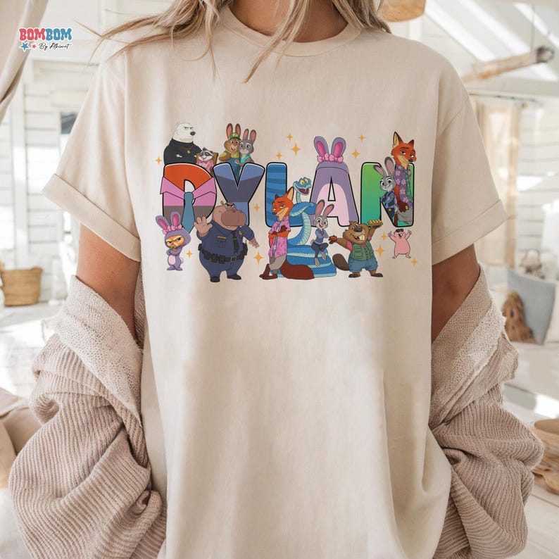 A person wearing a white t-shirt with a colorful graphic design featuring cartoon characters and the name "Dylan".