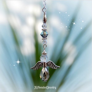 May include: A silver angel pendant with clear and iridescent crystal beads. The angel features detailed wings and a faceted crystal body. The pendant hangs from a delicate chain. The text "JG Beaded Jewelry" is at the bottom.