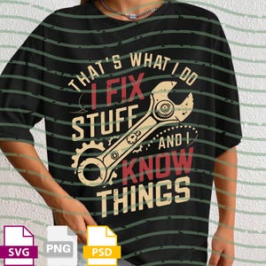 May include: Black t-shirt with the text "THAT'S WHAT I DO I FIX STUFF AND I KNOW THINGS" in white, red, and beige. The graphic includes a wrench and gear design. The shirt is a casual wear item.