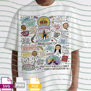 May include: White t-shirt featuring a colorful graphic design with the word "HAMILTON" and various illustrations and text elements. The design includes phrases like "Young, Scrappy, and Hungry" and "You Want a Revolution".