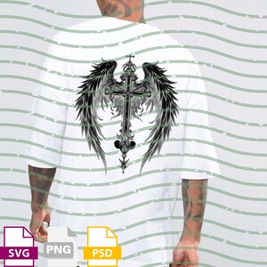 May include: White t-shirt featuring a detailed black and gray cross design with angel wings on the back. The cross has ornate detailing and a crown at the top. The wings are feathered and spread out. The shirt is a simple, casual style.