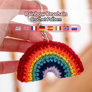 Può includere: Un portachiavi arcobaleno all'uncinetto con un portachiavi argentato. L'arcobaleno è fatto di filato rosso, arancione, giallo, verde, blu e viola. Il testo "Rainbow Keychain Crochet Pattern" è sopra il portachiavi.