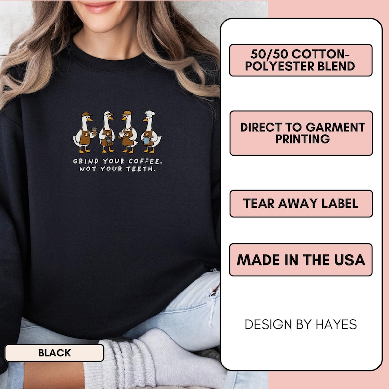 May include: Black sweatshirt featuring a design of four geese in aprons and hats, holding coffee cups. The text reads "GRIND YOUR COFFEE. NOT YOUR TEETH." It's made from a 50/50 cotton-polyester blend and printed directly onto the garment.