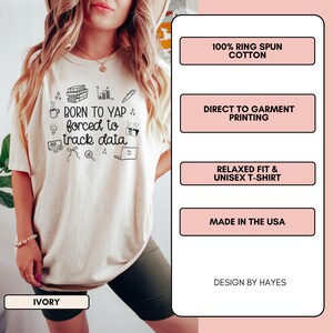May include: Ivory-colored unisex t-shirt with the text "BORN TO YAP forced to track data" and related graphics. Features include 100% ring-spun cotton, direct-to-garment printing, and a relaxed fit. Made in the USA.