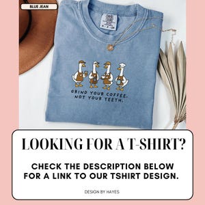 May include: Pale blue t-shirt featuring a cartoon design of four geese serving coffee, with the text "GRIND YOUR COFFEE. NOT YOUR TEETH." The shirt also has the text "LOOKING FOR A T-SHIRT? CHECK THE DESCRIPTION BELOW FOR A LINK TO OUR TSHIRT DESIGN."