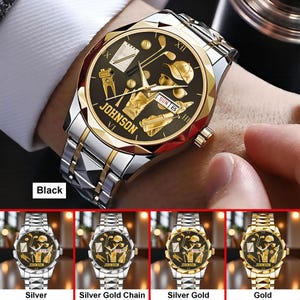 May include: A gold and silver wristwatch with a black face featuring golf-themed designs. The watch has a silver band with gold accents and the brand name "JOHNSON" is visible. The date is displayed as "SUN 8".