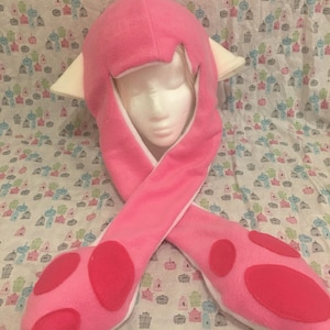 May include: Pink hooded hat with white ears and paw-shaped ends. The hat is made of soft fleece and has a white lining.