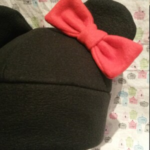 May include: Black fleece hat with large, floppy red bow and mouse ears.