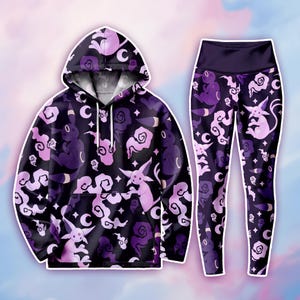 May include: A matching black hoodie and leggings set. The hoodie has a drawstring hood and a kangaroo pocket. Both items are patterned with purple and pink cartoon characters, moons, and clouds. The leggings have a high waistband.