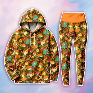 May include: A long-sleeve hooded sweatshirt and matching high-waisted leggings featuring an all-over print of various cartoon creatures, orange pumpkins, and red mushrooms on a dark brown background. The hoodie includes white drawstrings.