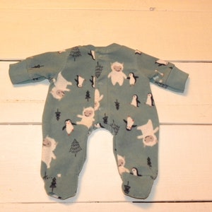 May include: A green baby onesie with a white yeti and penguin print.