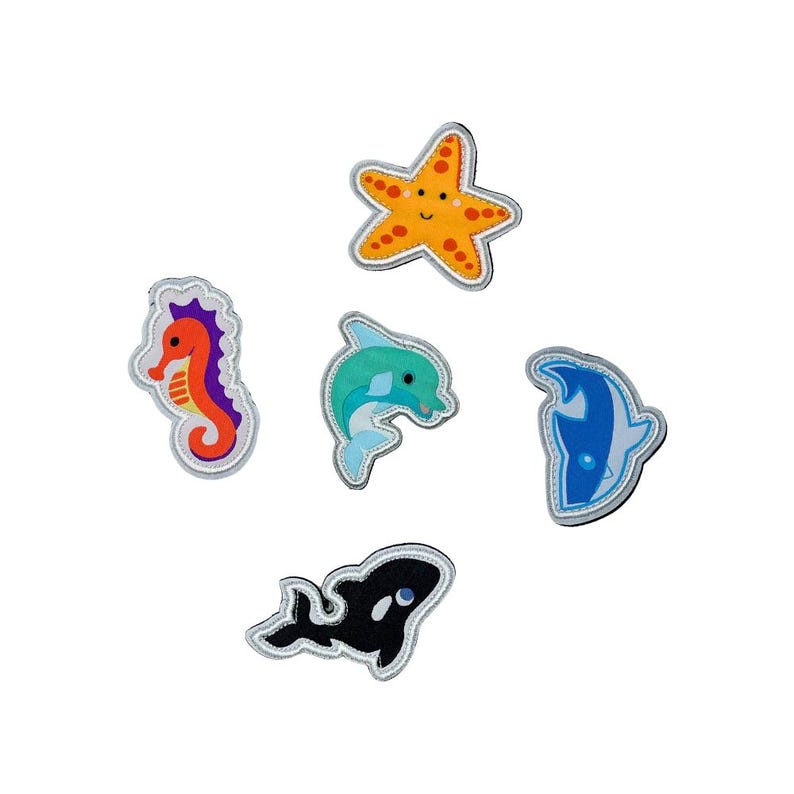 May include: Six felt ocean animal patches, including a starfish, a seahorse, a dolphin, a shark, and an orca whale. The patches are all brightly colored and have a white outline.