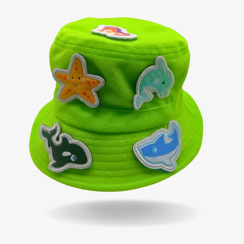 May include: A bright green bucket hat with various colorful sea creature patches, including a starfish, a dolphin, a shark, and a whale.