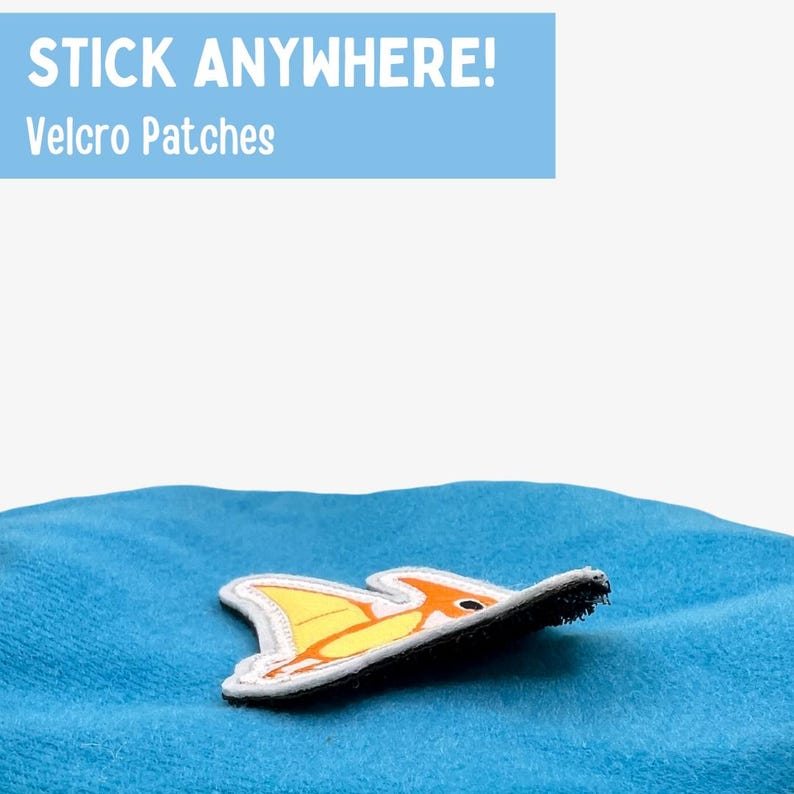 May include: A yellow and orange cartoon fish velcro patch on a blue fabric surface. The text "STICK ANYWHERE! Velcro Patches" is in the top left corner of the image.