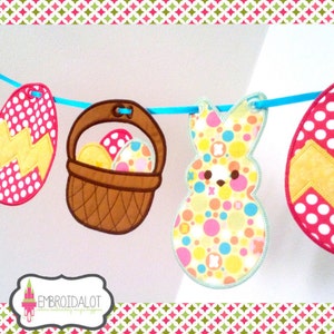 May include: A colorful Easter banner with a bunny, eggs, and baskets. The banner is made of felt and has a blue ribbon running through it. The bunny is yellow with pink and blue polka dots. The eggs are red with white polka dots and yellow with a zig-zag pattern. The baskets are brown with a white handle.