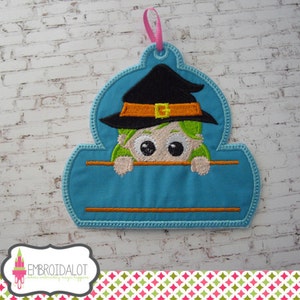 May include: A blue and green Halloween-themed name tag with a witch peeking over the top. The tag has a space for a name to be added.