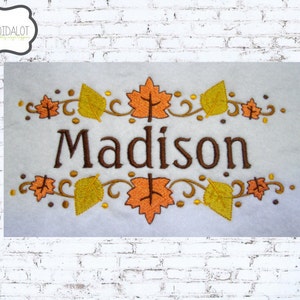 May include: Embroidered design featuring the name "Madison" in brown thread, surrounded by a border of orange and yellow leaves and vines.