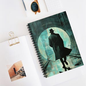 May include: Spiral-bound notebook featuring a noir-style illustration of a man in a hat and trench coat walking away. The cover art has a teal and gray color scheme with a circular design element. The notebook is open on a white surface.
